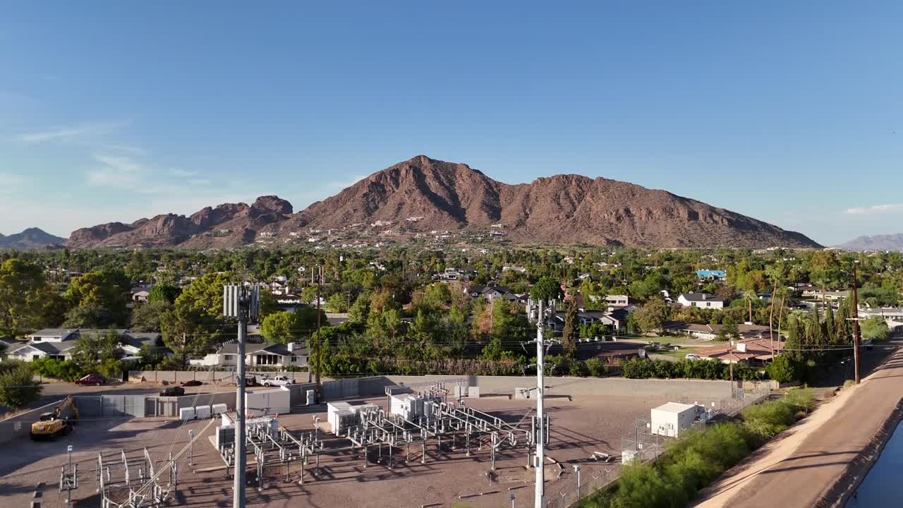 Drone Ascending over canal Showing Camelback Mountain with houses, trees, and cellphone towers