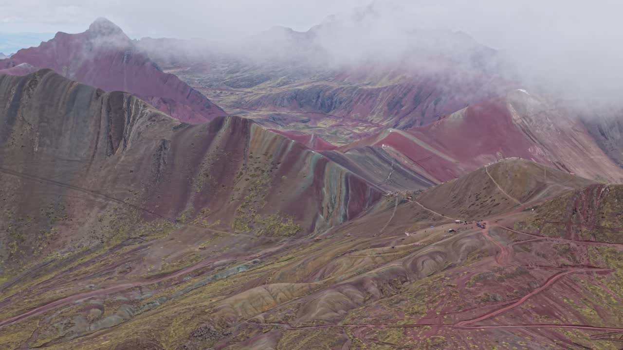 Aerial of Rainbow Mountain's colorful peaks under cloudy skies in Peru