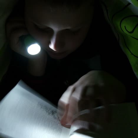 child reading at night with flashlight