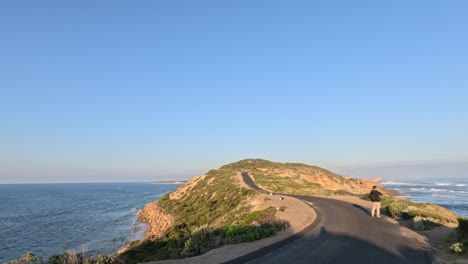 man walking along scenic coastal road