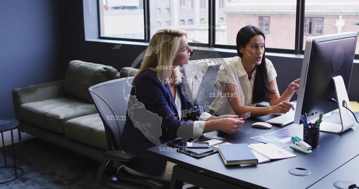Two Professional Women Collaborating on a Project in a Modern Office