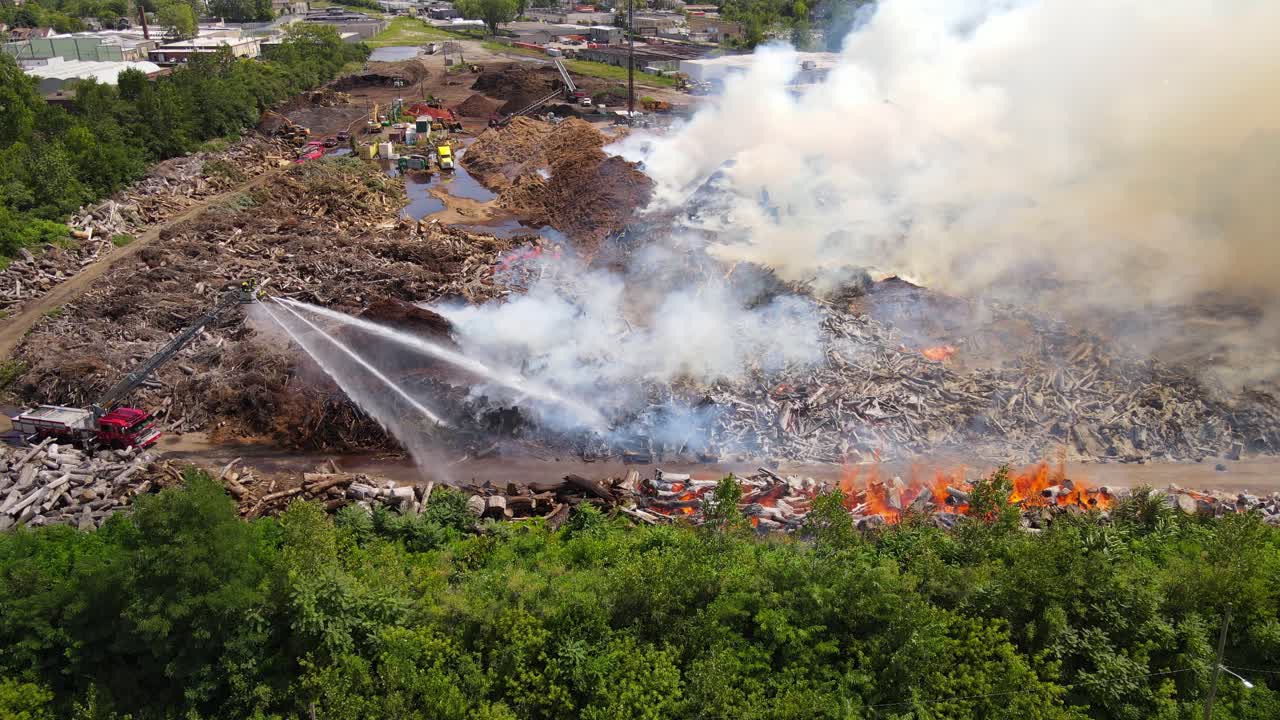 Firefighters pour water on burning mulch company, aerial view