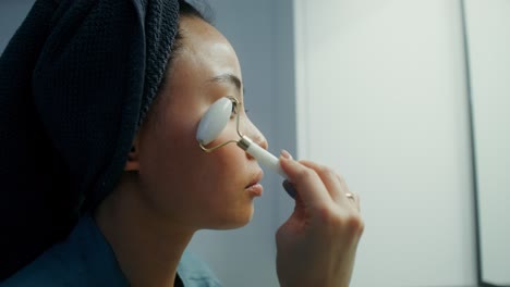 woman using jade roller for facial massage