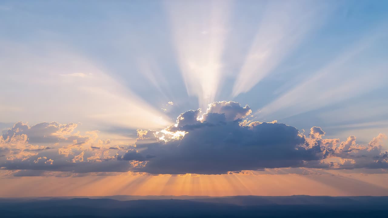 Blocking large cumulus cloud revealing golden horizon at sunset sun peeking behind creating rays