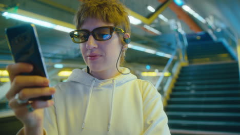 woman in earphones using smartphone on subway station