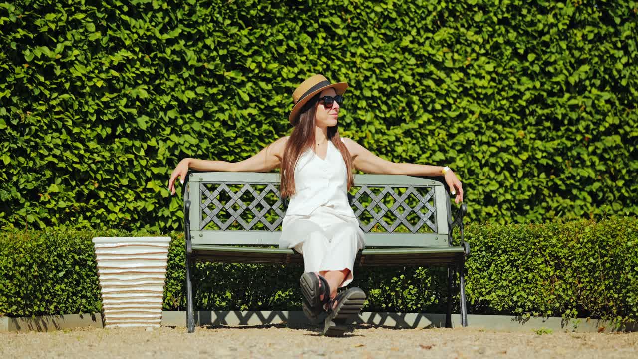 Slow motion portrait of woman near manicured hedge in French Baroque garden