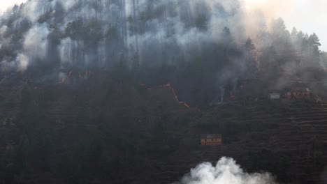 a wildfire burning a steep hillside in nepal in the dry season with smoke reaching into the sky