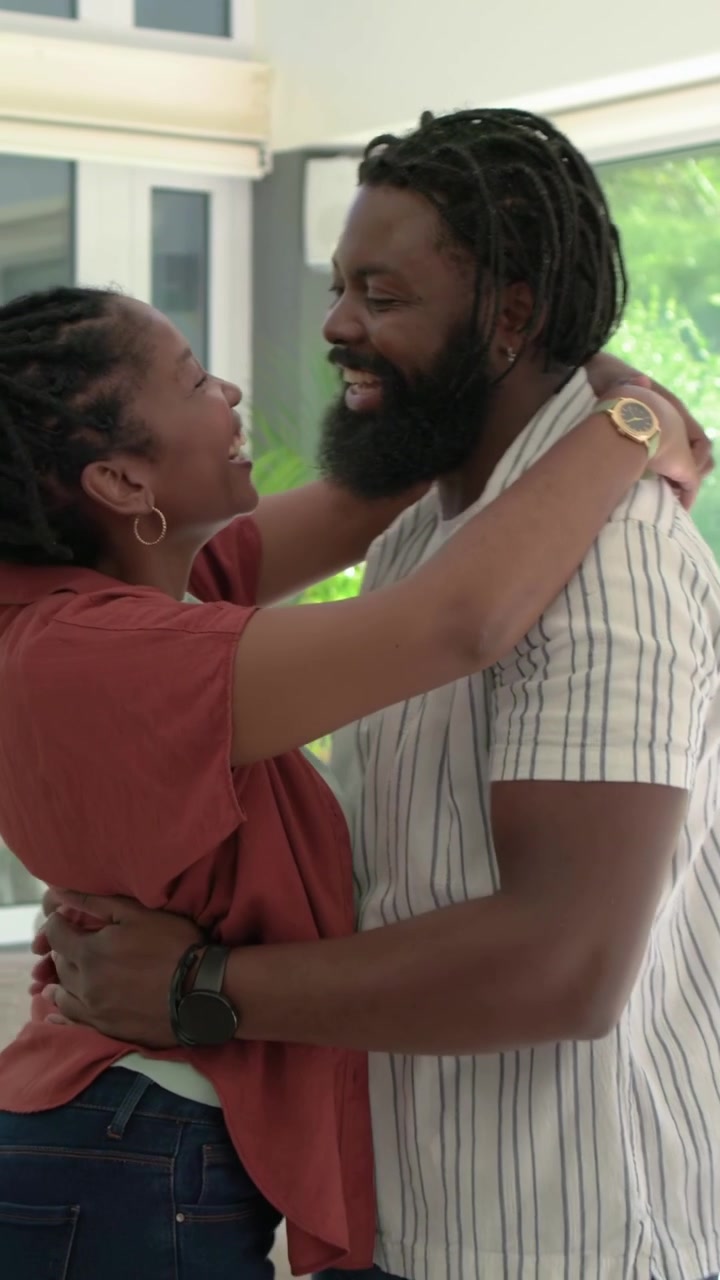 Vertical video: Wrapping arms around man rust top woman lifting, swaying near windows showing love