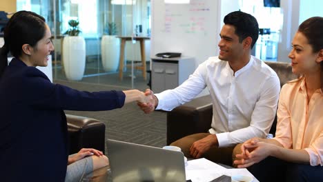 Business-colleagues-shaking-hands-in-office