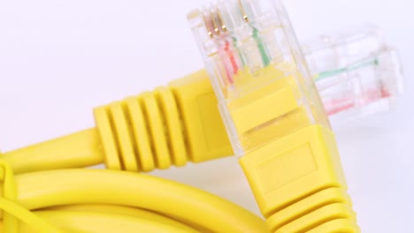 cable ethernet amarillo girando sobre una superficie blanca, toma macro