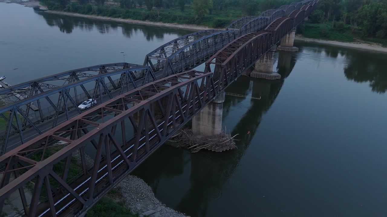 Record low Po River levels expose extensive sandbanks and sediment around bridge piers beneath the historic railway and parallel road bridges, documenting severe hydrological drought across Po Valley.