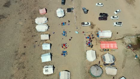 Aerial-drone-top-down-view-of-cars,-tents-and-yurts-at-a-dirt-campground-in-the-high-altitude-alpine-plain-of-Deosai-National-Park-located-between-Skardu-and-Astore-Valley-in-Pakistan-on-a-sunny-day