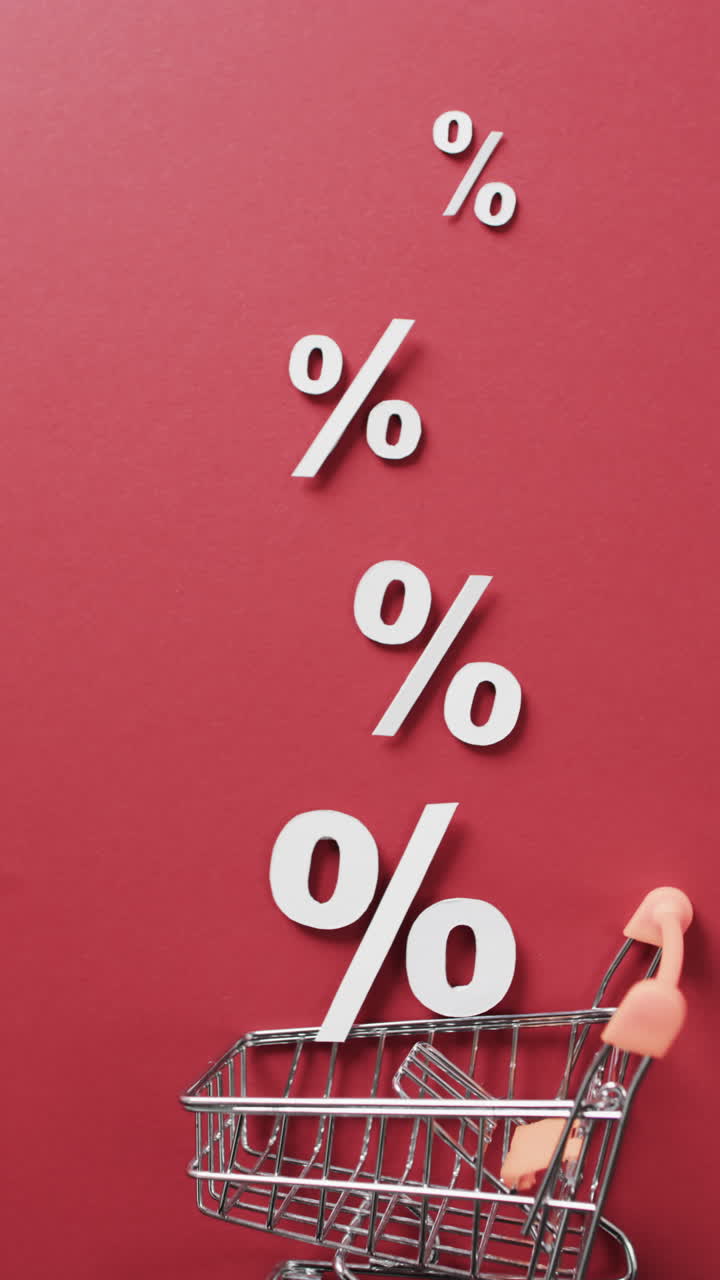 Vertical video of shopping trolley and white percent signs on red background