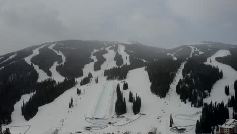 Luftdrohne-Kupfer-Berg-Colorado-Ikone-Epischer-Pass-Winter-Frühling-Bewölkt-Verschneit-Früher-Morgen-Erster-Hellgrauer-Vogel-Halfpipe-Sessellift-Skipisten-Zentrum-Dorf-Gondel-Filmischer-Kreis-Langsam-Links