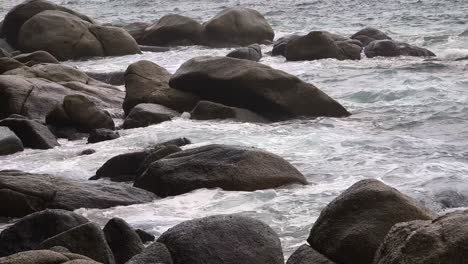 ocean waves crashing against dark coastal boulders