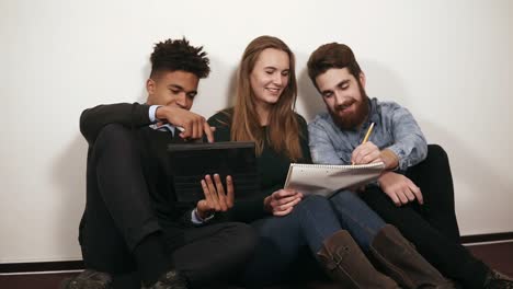 un grupo diverso de estudiantes o un equipo de jóvenes empresarios trabajando en un proyecto. están sentados en el suelo y trabajando con