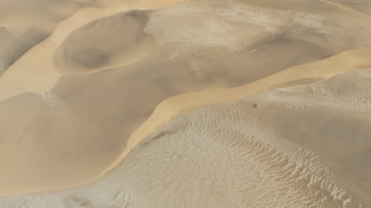 Drone view over the vast Namib Desert dunes, with soft shadows and textures sculpted by the coastal winds of Swakopmund, Namibia