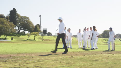 playing cricket, female team celebrating on field with umpire walking away