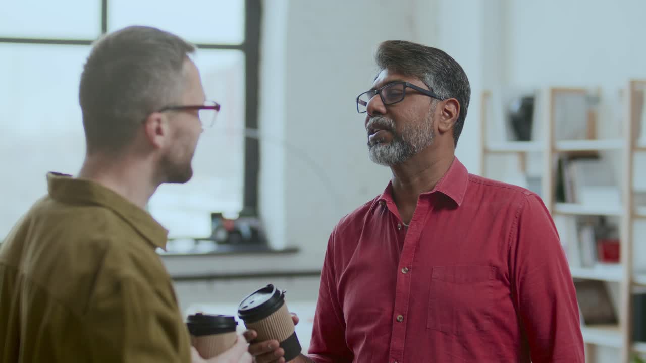 Middle-Aged Indian Man Talking with Colleague on Coffee Break in Office