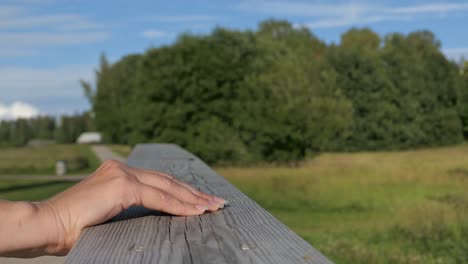 woman hand touching wooden bridge handrail in countryside