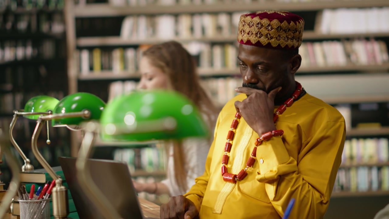 Smiling adult learner working at library table with desktop computer