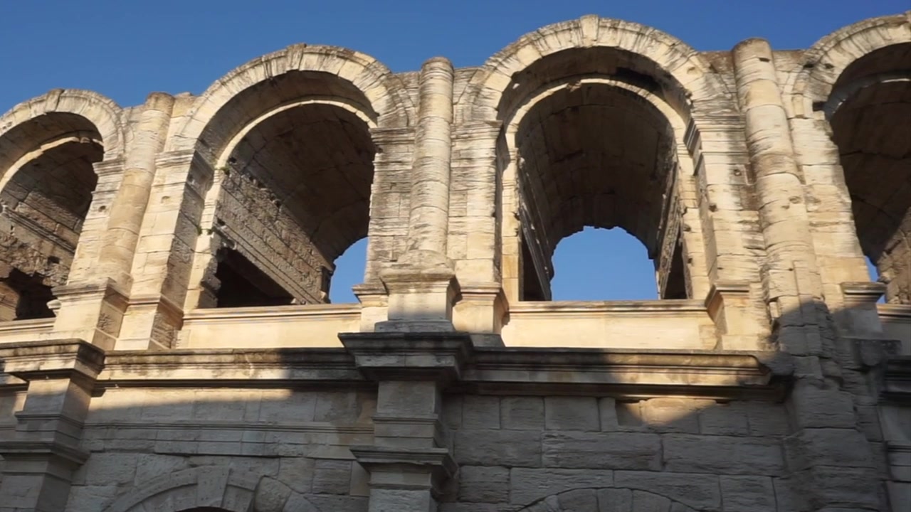 Vista ravvicinata dell'antico Teatro Romano di Arles, con archi e colonne monumentali in pietra sotto un cielo azzurro e limpido in Provenza, Francia.