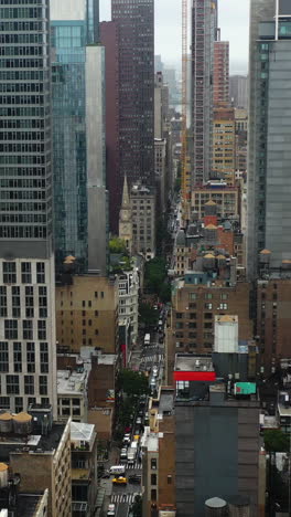 vertical drone shot in middle of skyscrapers in misty midtown, new york, usa