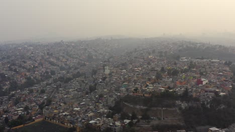 Aerial-drone-shot-of-big-urban-settlements-in-ravines-in-a-very-polluted-day-in-Mexico-City