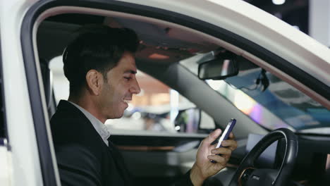 man looking at phone in car at auto show