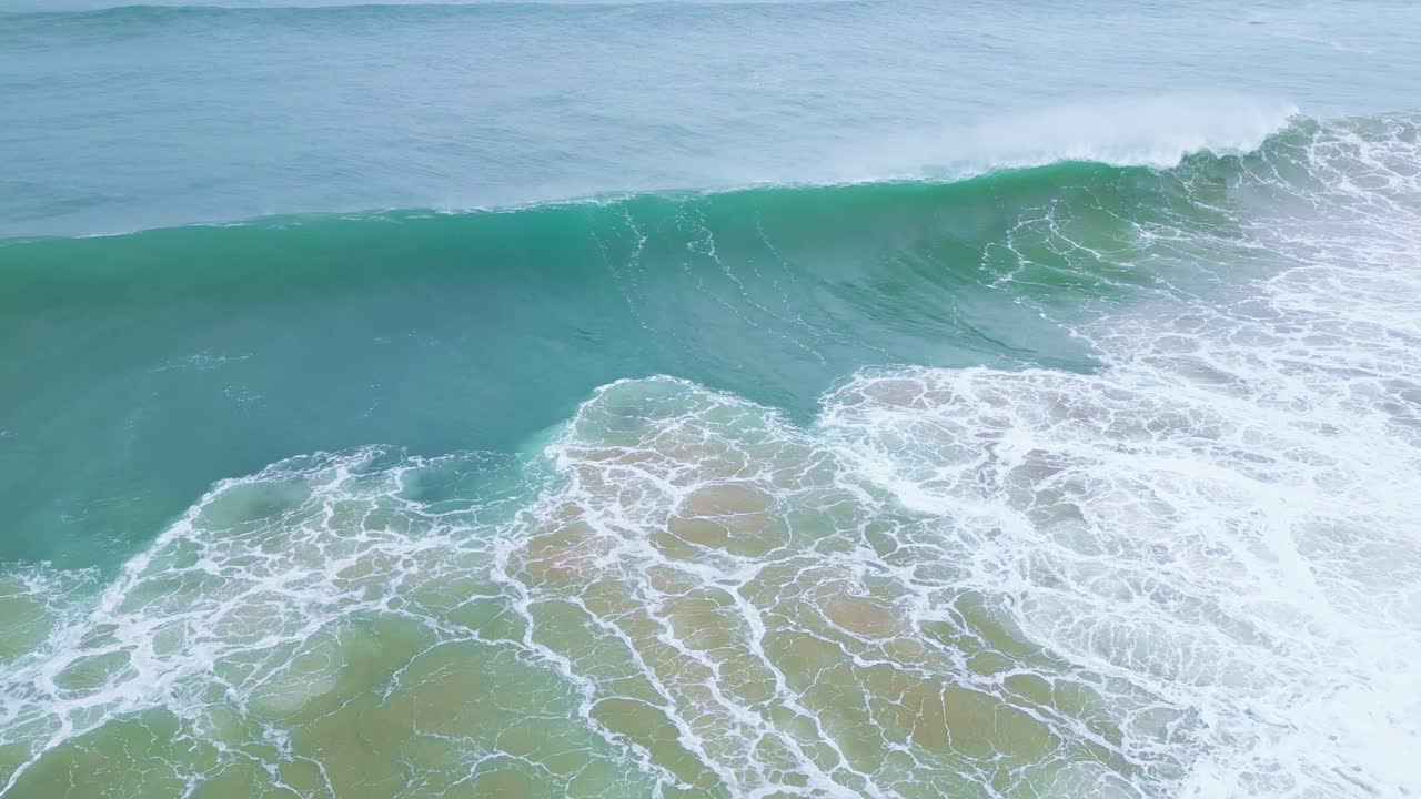 Gentle waves crashing on the beach in Aljezur, Portugal with a serene blue ocean view
