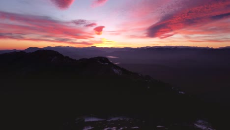 Silueta-Vista-Aérea-Volando-Hacia-Adelante-Durante-Una-Increíble-Puesta-De-Sol-Colorida-En-Invierno-Con-Nieve-En-Los-Picos-De-Las-Montañas-En-Madrid,-España