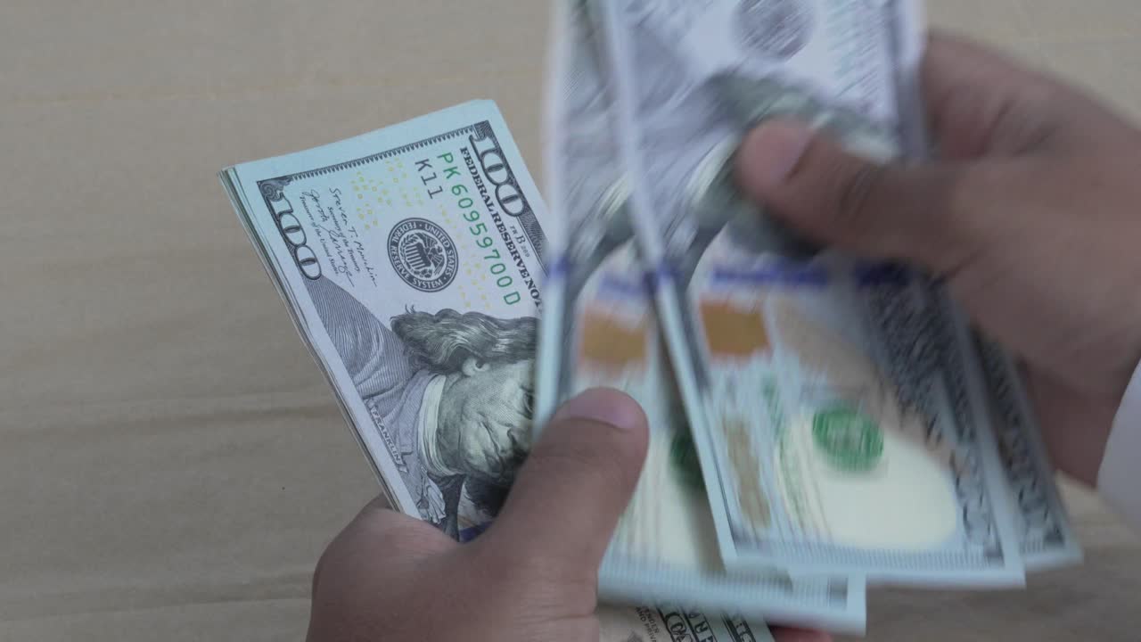 Nærbillede af hænder, der tæller en stak hundrede dollarsedler, koncept for finansielle detaljer 4K video