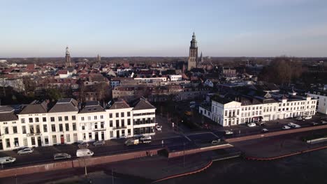 Autos-Und-Verkehr-Passieren-Die-Weiße-Fassade-Der-Stadt-Entlang-Des-Flusses-Ijssel-Mit-Mittelalterlichen-Türmen-Des-Historischen-Stadtzentrums-Im-Hintergrund