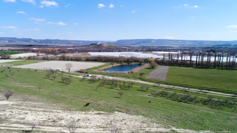 aerial view of a farmland landscape with greenhouses and a pond