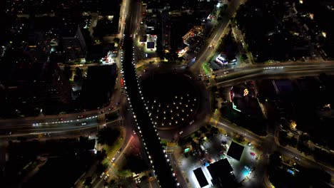 aerial view at night of a large traffic circle with dozens of vehicles in congested traffic