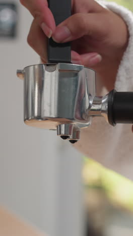 una mujer vierte café en un portafiltro en una mesa de primer plano. una mujer con una túnica esponjosa llena el recipiente con café molido en casa. preparación de bebidas