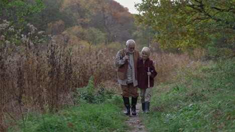 grandfather and grandson walking with fishing rods through an autumn landscape
