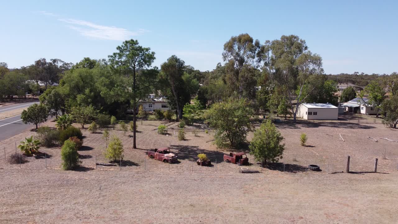 drone descendiendo en una remota ciudad del interior que muestra coches viejos oxidados
