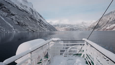 slow motion pov of a winter ferry boat ride in geirangerfjord to geiranger, norway, with snowy mountains and captivating fjord views