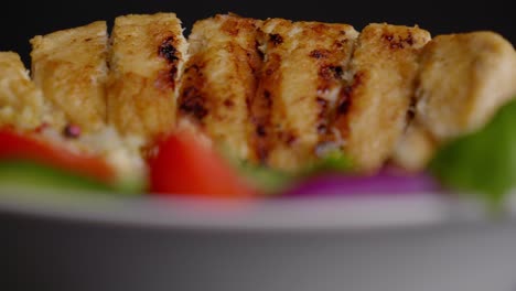 Extreme-close-up-of-a-bowl-of-grilled-vegan-meat-and-fresh-vegetables-on-a-bed-of-rice,-cucumber,-red-onion,-and-tomatoes,-cut-out