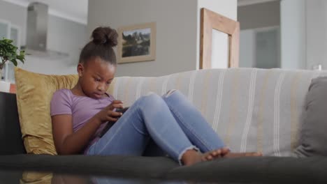 african american girl sitting on sofa and using tablet, slow motion, unaltered