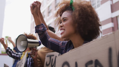 Eine-Vielfältige-Gruppe-Von-Männern-Und-Frauen-Hält-Plakate-Hoch-Und-Schreit-Während-Des-Protests-Mit-Einem-Megafon