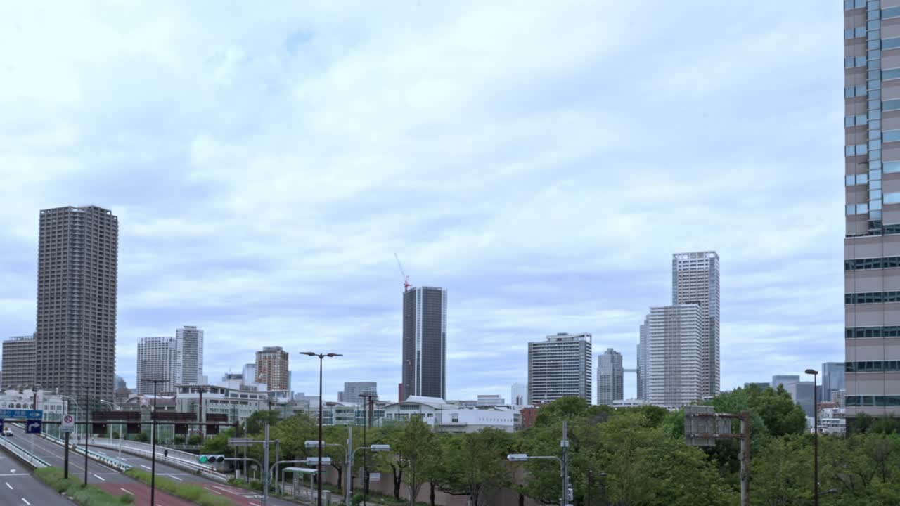 A wide shot of the Tokyo skyline with modern skyscrapers against a dramatic, cloudy sky