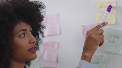 mixed race business woman using sticky notes training intern brainstorming with colleague sharing creative ideas for problem solving solution in office