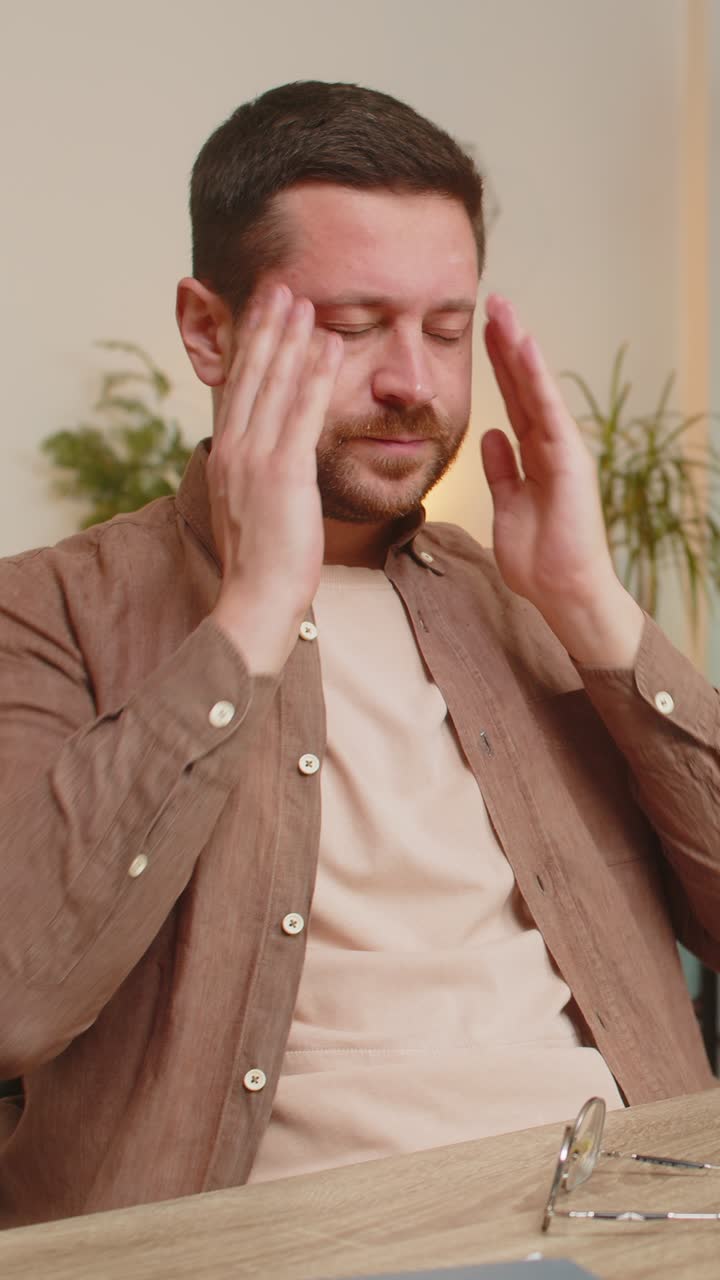 Overworked businessman suffering from eye strain and headache working on laptop sitting at table
