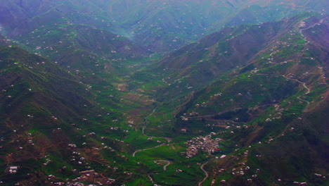 Aerial-flight-over-the-most-spectacular-and-the-epic-scenery-with-towering-hills,-village,-river-and-houses