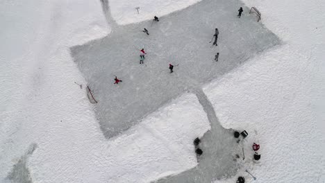 overhead aerial drone view of kids playing hockey on a frozen pond