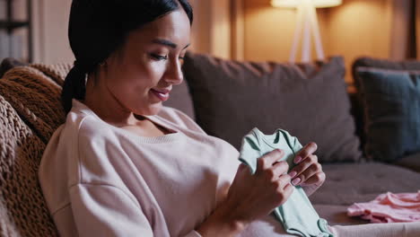 pregnant woman looking at baby clothes