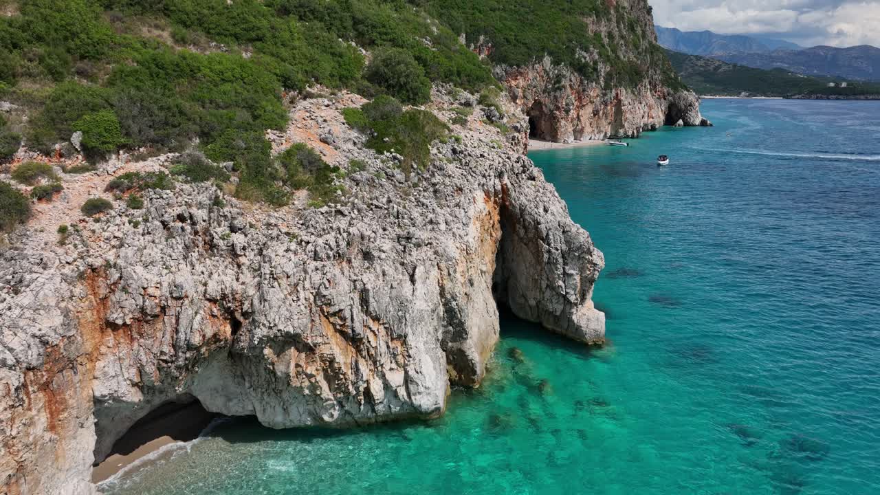 Drone tracking along bright turquoise water and rocky coastline at Gjipe Beach, Albania