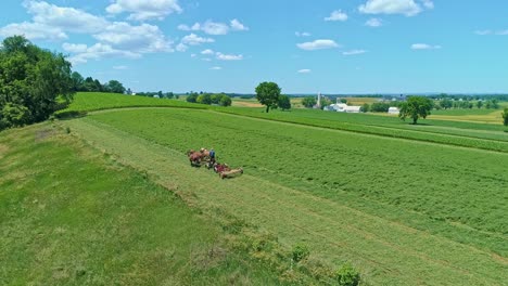 Eine-Luftaufnahme-Eines-Amish-Bauern-Mit-Drei-Pferden,-Die-An-Einem-Schönen-Tag-über-Die-Landschaft-Ernten